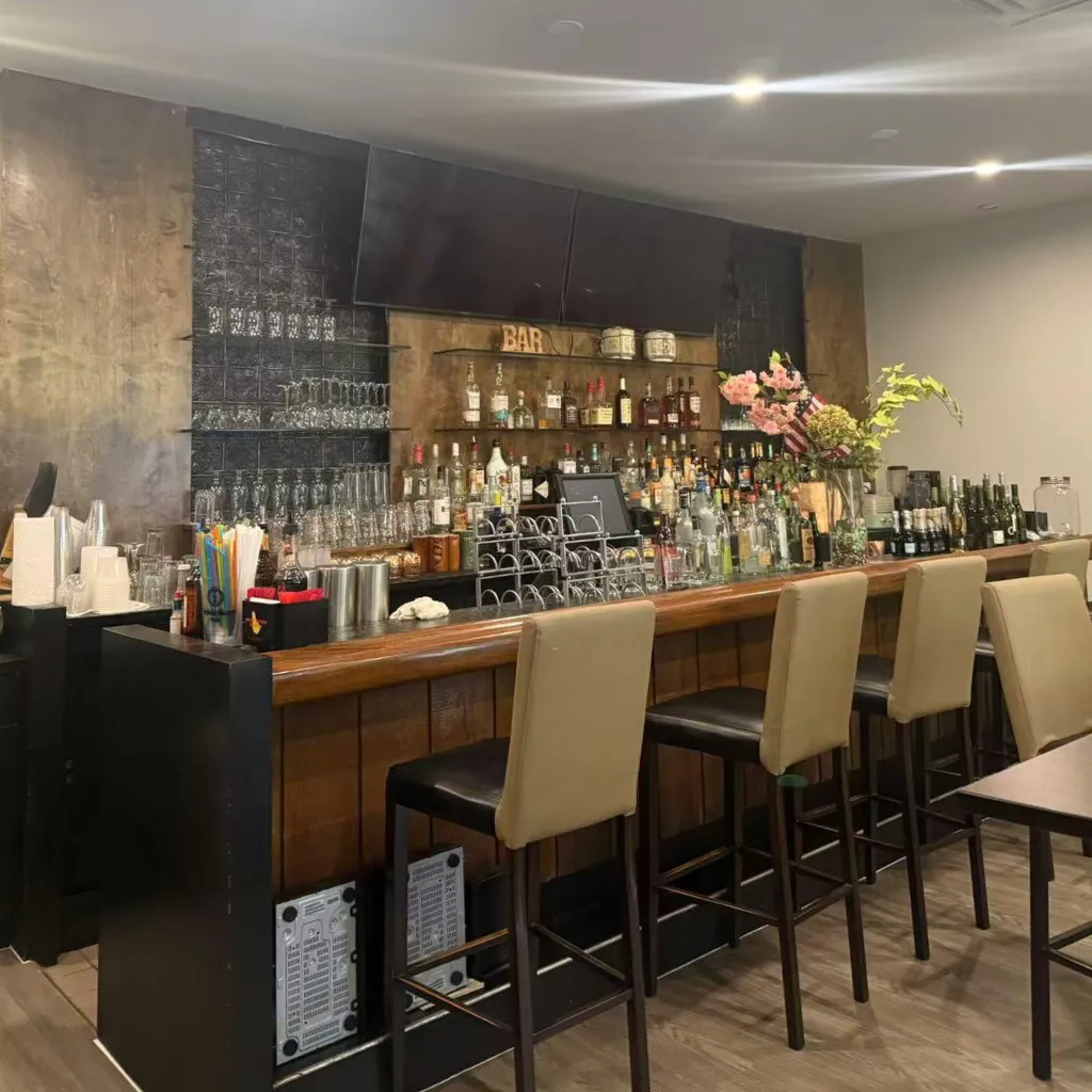 Well-stocked bar counter with various liquors and bar stools at Asian Moon Sushi And Bar, a Japanese Restaurant in Cross River